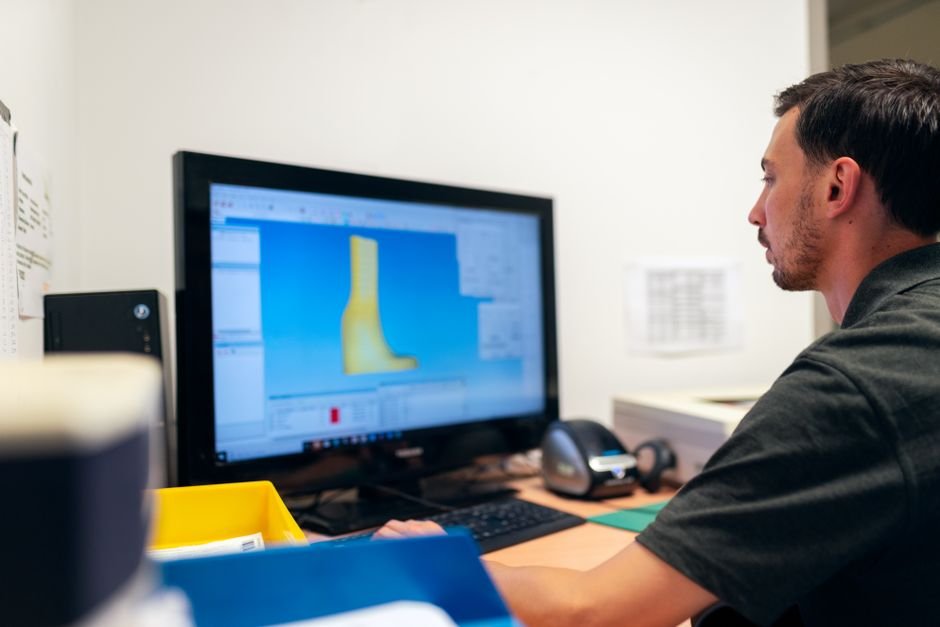 Engineer working on prosthetic design using specialized software in an office setting